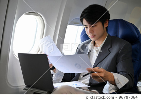 Asian businessman concentrating working, preparing a meeting documents during the flight 96787064