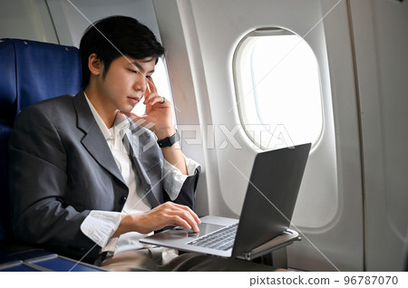 Professional Asian businessman working on his project, using laptop during the flight 96787070