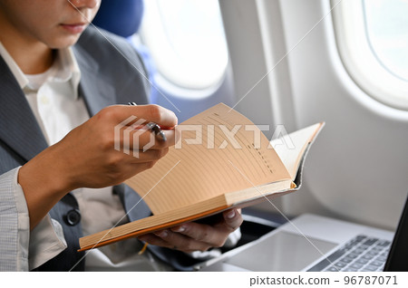 Successful Asian businessman reading a book during the flight for his business trip. cropped Successful Asian businessman reading a book during the flight for his business trip. cropped 96787071