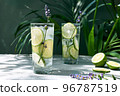 Cool lavender lemonade with lime slices and lavender flower on the table near dark green wall and palm leaves. Healthy organic summer soda drink. Detox water. Diet unalcolic coctail. 96787519
