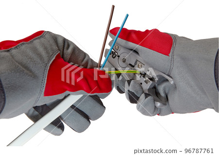 An electrician removes insulation from a three-core copper wire with a stripper cutter An electrician removes insulation from a three-core copper wire with a stripper cutter 96787761