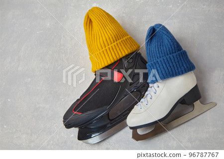 Men's and women's skates in knitted blue and yellow winter hats on a gray concrete background Men's and women's skates in knitted blue and yellow winter hats on a gray concrete background 96787767