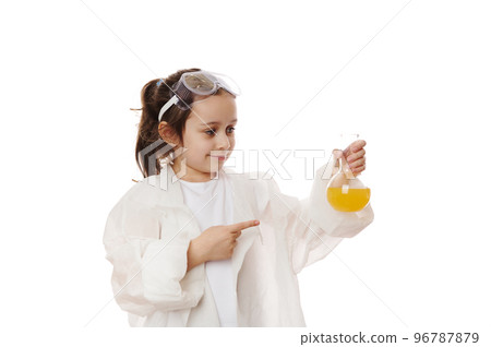 Smart little girl, student pointing at flask with yellow chemical liquid, doing scientific experiments in practical chemistry class. Young chemist scientist isolated on white background. Copy ad space 96787879
