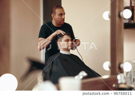Barber shaving caucasian man in barber shop 96788011