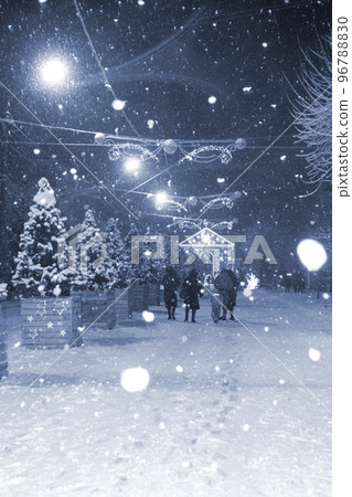 City street during heavy snowfall at winter night. Illumination decoration Lanterns garlands on Christmas tree. Blue color Christmas New Year Holidays celebration background. white spots of snowflakes City street during heavy snowfall at winter night. Illumination decoration Lanterns garlands on Christmas tree. Blue color Christmas New Year Holidays celebration background. white spots of snowflakes 96788830