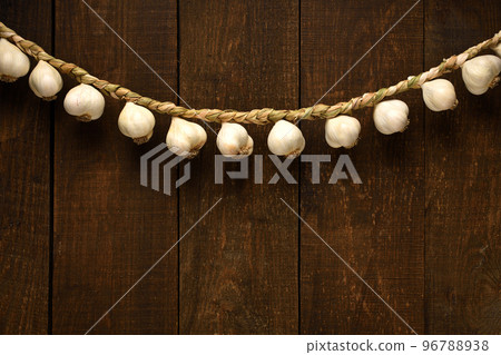 garlic bulbs braided in a pigtail like a garland on a background of dark wooden boards, an empty place for text garlic bulbs braided in a pigtail like a garland on a background of dark wooden boards, an empty place for text 96788938