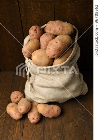 a sack full of potatoes on dark wooden background 96788962