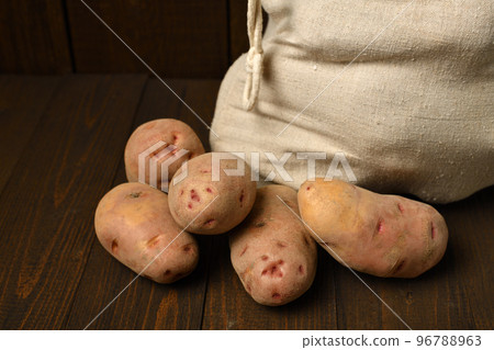 a sack full of potatoes on dark wooden background 96788963