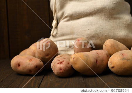 a sack full of potatoes on dark wooden background a sack full of potatoes on dark wooden background 96788964