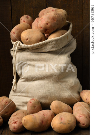 a sack full of potatoes on dark wooden background 96788965