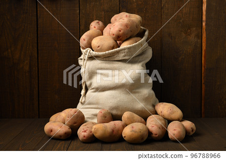 a sack full of potatoes on dark wooden background a sack full of potatoes on dark wooden background 96788966
