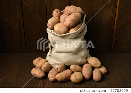 a sack full of potatoes on dark wooden background 96788969