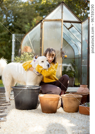 Woman with dog plant flowers in garden Woman with dog plant flowers in garden 96789190
