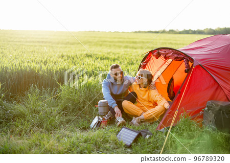 Young couple at campsite with tent on green field 96789320