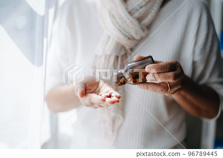 Focused mature lady examining drug prescription label at home.  holding bottle with pills in hands, reading instruction 96789445