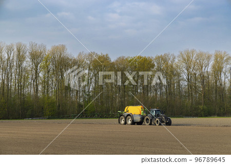 Tractor with a sprayer during spring work in the field 96789645