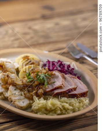 smoked meat served with red and white cabbage and two kinds of dumplings 96789709