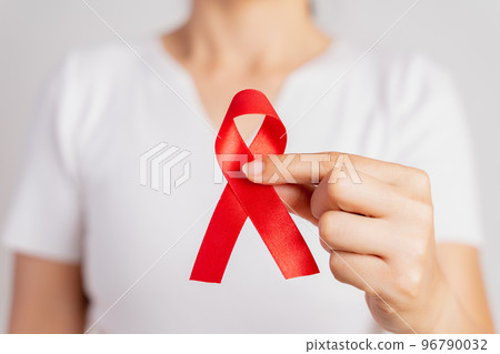 Closeup woman hand holding red ribbon HIV, world AIDS day awareness ribbon. Healthcare and medicine concept. 96790032