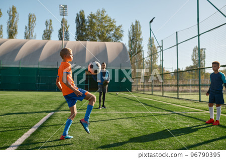 Young boys playing football soccer match at training camp for kids Young boys playing football soccer match at training camp for kids 96790395