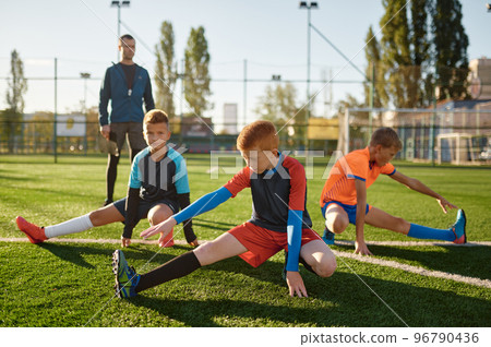 Young boys football players doing warm up workout stretching legs 96790436