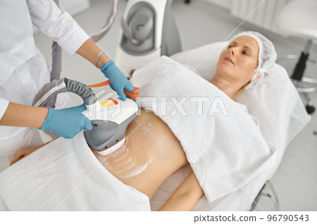 Doctor cosmetologist doing vacuum massage procedure on woman belly Doctor cosmetologist doing vacuum massage procedure on woman belly 96790543
