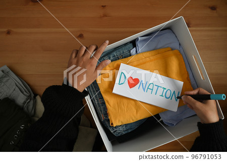 Woman packing clothes into donation box. Charity, donation and reuse recycle concept 96791053