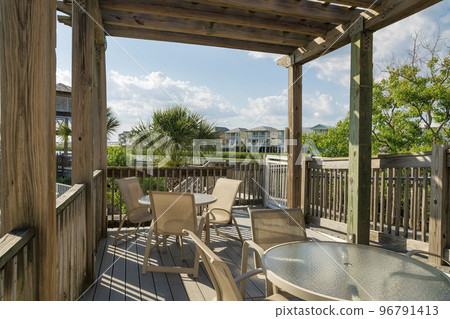 Destin, Florida- Wooden deck with coffee tables and chairs against the lake view 96791413