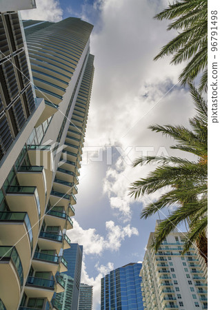 High-rise condominium buildings in a low angle view under the sun behind the puffy clouds- Miami, FL 96791498