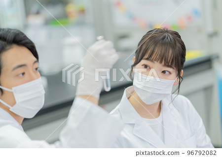 Men and women having a conversation while looking at test tubes in a university laboratory Men and women having a conversation while looking at test tubes in a university laboratory 96792082