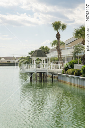 View of a gazebo on a deck over the brackish water of a lake with steel retaining wall at Destin, FL 96792497