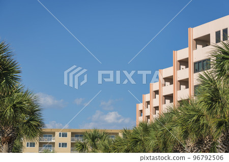 Destin, Florida- Rows of palm trees and residential buildings against the blue sky Destin, Florida- Rows of palm trees and residential buildings against the blue sky 96792506