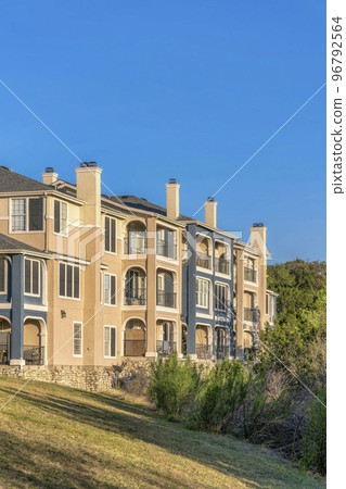 Austin, Texas- Three-storey apartment building on top of a grassy slope near Lake Austin 96792564