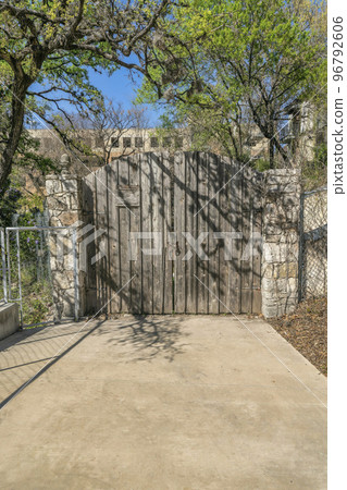 Rustic and old arched wooden gate at the entrance of a private property 96792606