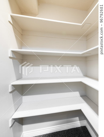 Vertical White linen closet with wall mounted shelves and carpeted floor 96792681