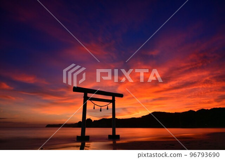 A torii standing on the sea dyed in the bright red sunset 96793690