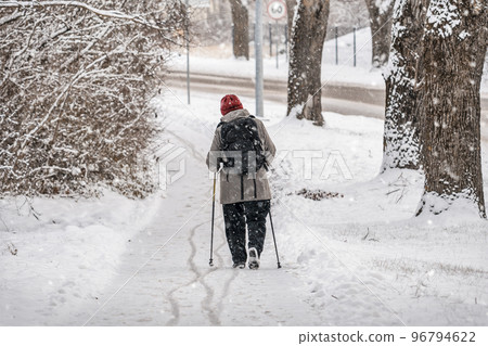 An elderly woman trains Nordic walking with sticks 96794622