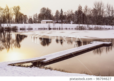 Golden sunrise above a jetty on a frozen winter lake Golden sunrise above a jetty on a frozen winter lake 96794627