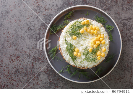 Classic mimosa salad with potatoes, canned fish, carrots, eggs and cheese seasoned with mayonnaise close-up on a plate. Horizontal top view 96794911