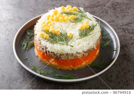 Classic mimosa salad with potatoes, canned fish, carrots, eggs and cheese seasoned with mayonnaise close-up on a plate. Horizontal Classic mimosa salad with potatoes, canned fish, carrots, eggs and cheese seasoned with mayonnaise close-up on a plate. Horizontal 96794918