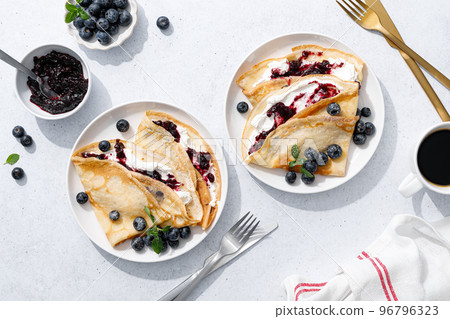 Crepes with blueberry jam, ricotta cheese and fresh berries. Pancakes for breakfast. Top view Crepes with blueberry jam, ricotta cheese and fresh berries. Pancakes for breakfast. Top view 96796323