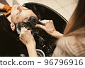 Young man getting a modern haircut. Hair salon master washing client hair at barber shop. Men's 96796916