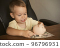 Child dollar banknote piggy bank in the table. Smart happy boy saving money in a piggy bank 96796931