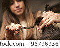 Hair care, beauty industry concept. Hairdresser doing haircut closeup of work. Hairstylist does 96796936