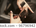 Hairstylist does cutting hair tips of a female customer in a beauty salon. Womens fashion and style 96796942