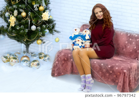 Young pretty woman on sofa near festive new year christmas tree Young pretty woman on sofa near festive new year christmas tree 96797342