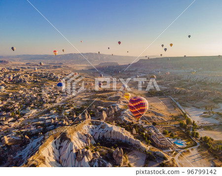 Colorful hot air balloons flying over at fairy chimneys valley in Nevsehir, Goreme, Cappadocia Turkey. Spectacular panoramic drone view of the underground city and ballooning tourism. High quality Colorful hot air balloons flying over at fairy chimneys valley in Nevsehir, Goreme, Cappadocia Turkey. Spectacular panoramic drone view of the underground city and ballooning tourism. High quality 96799142