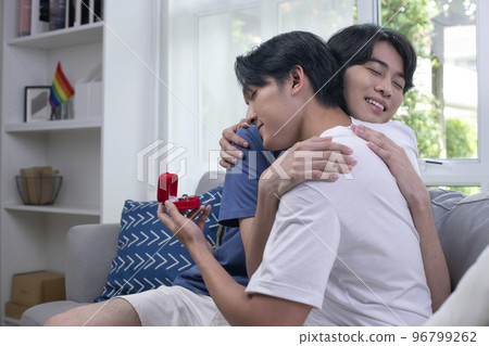 Engaged men couple hugging each other lovingly in living room Engaged men couple hugging each other lovingly in living room 96799262