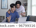 Asian gay couple holding credit card and using laptop computer 96799316