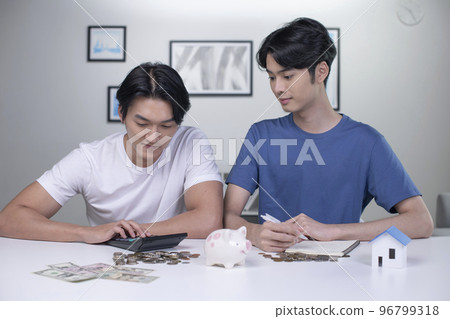 Asian gay couple saving money to buy a house Asian gay couple saving money to buy a house 96799318