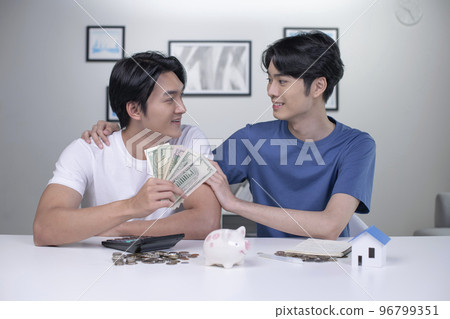 Asian gay couple saving money to buy a house Asian gay couple saving money to buy a house 96799351